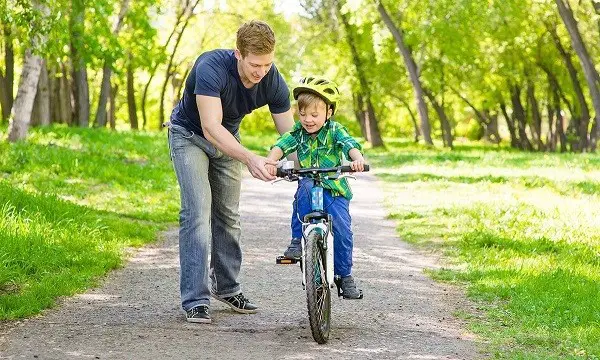 bērna braukšana ar divriteņu velosipēdu.